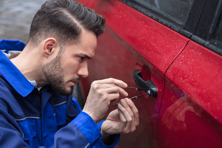 A locksmith opening a car door with a key
